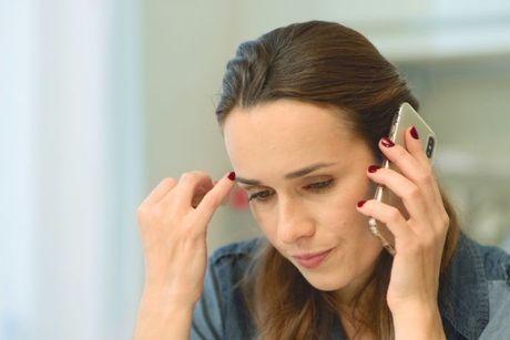 A woman looking annoyed on her phone calling a customer service for EE payment arrangement plan.